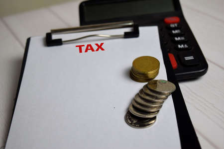 Tax write on paperwork on clipboard and the stack of coint. Finance or Tax Conceptの写真素材
