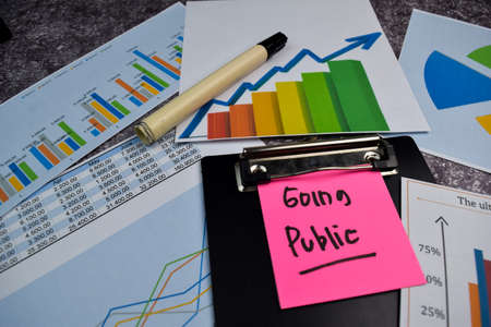 Going Public write on sticky notes isolated on Office Desk. Stock market concept