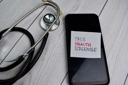 Free Health Screening write on sticky notes above a smartphone and stethoscope isolated on office...