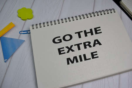 Go The Extra Mile write on a book isolated on office deskの写真素材