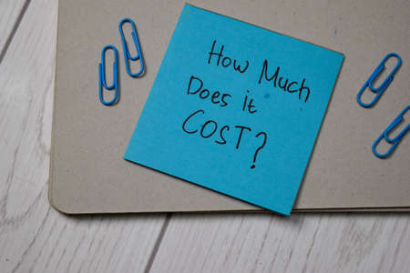 How Much Does it Cost? write on sticky note isolated on wooden table.の写真素材