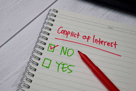 Conflict of Interest write on a sticky note. Supported by an additional services isolated wooden...