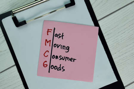 FMCG - Fast Moving Consumer Goods write on sticky note isolated on Wooden Table.の写真素材