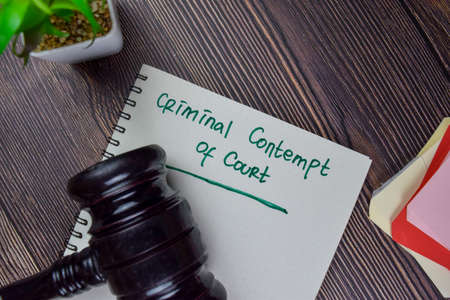 Criminal Contempt of Court write on a book isolated on Wooden Table.の写真素材