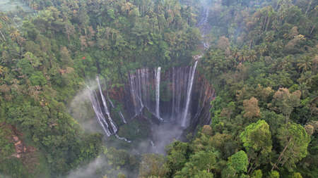 Aerial view of Tumpak Sewu waterfall and Semeru mountain at sunrise located in Lumajang. East Java, Indonesia, August 28, 2022の写真素材