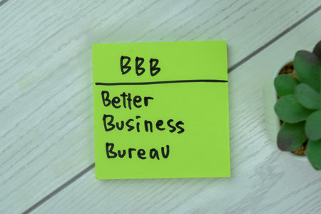 Concept of BBB - Better Business Bureau write on sticky notes isolated on Wooden Table.の写真素材