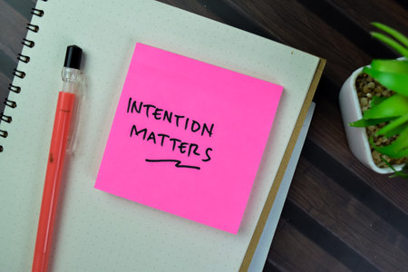 Concept of Intention Matters write on sticky notes isolated on Wooden Table.