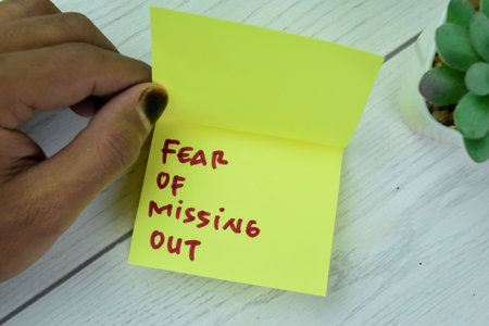 Concept of FOMO - Fear Of Missing Out write on sticky notes isolated on Wooden Table.の写真素材