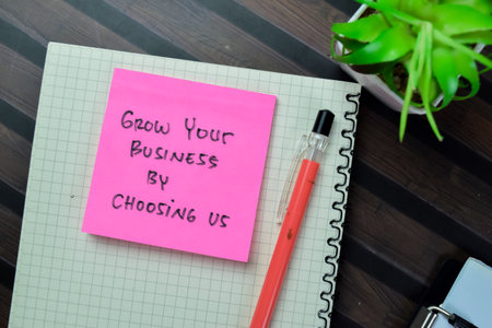 Concept of Grow Your Business by Choosing Us write on book isolated on Wooden Table.の写真素材