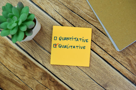 Concept of Quantitative and Qualitative write on sticky notes isolated on Wooden Table.の写真素材