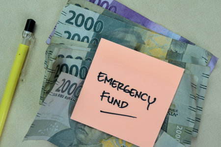 Concept of Emergency Fund write on sticky notes with Indonesian Currency isolated on Wooden Table.の写真素材