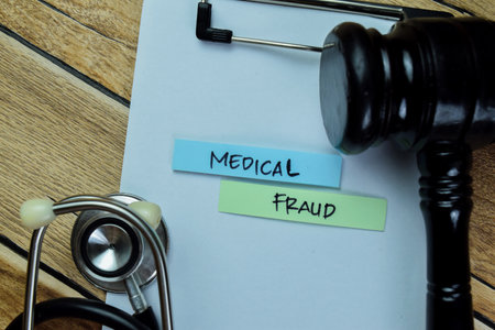 Concept of Medical Fraud write on sticky notes with stethoscope and gavel isolated on Wooden Table.の写真素材