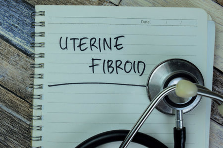 Concept of Uterine Fibroid write on book with stethoscope isolated on Wooden Table.