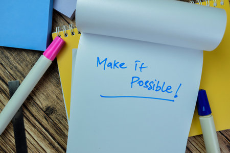 Concept of Make it Possible! write on book isolated on Wooden Table.