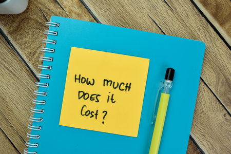 Concept of How Much Does it Cost? write on sticky notes isolated on Wooden Table.