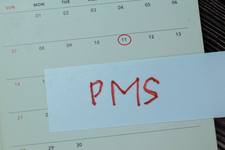Concept of PMS write on sticky notes with calendar isolated on Wooden Table.の写真素材