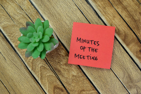 Concept of Minutes of The Meeting write on sticky notes isolated on Wooden Table.の写真素材