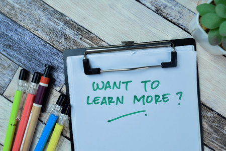 Concept of Want To Learn More? write on paperwork isolated on Wooden Table.