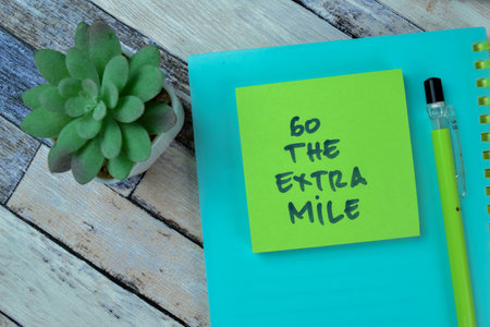 Concept of Go The Extra Mile write on sticky notes isolated on Wooden Table.の写真素材