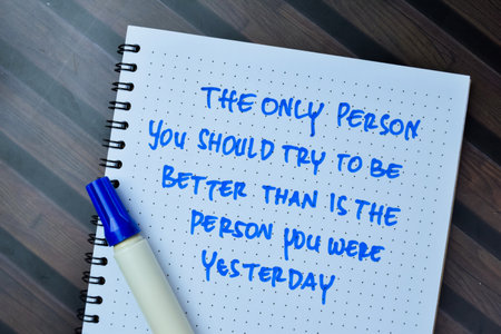 Concept of The Only Person You Should Try To Be Better Than Is The Person You Were Yesterday write on book isolated on Wooden Table.の写真素材