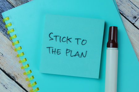 Concept of Stick to the Plan write on sticky notes isolated on Wooden Table.の写真素材