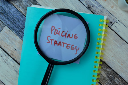 Concept of Pricing Strategy write on sticky notes isolated on Wooden Table.