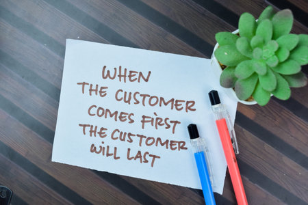 Concept of When The Customer Comes First The Customer Will Last write on sticky notes isolated on Wooden Table.の写真素材