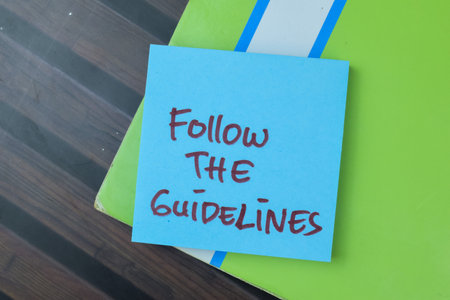 Concept of Follow The Guidelines write on sticky notes isolated on Wooden Table.の写真素材