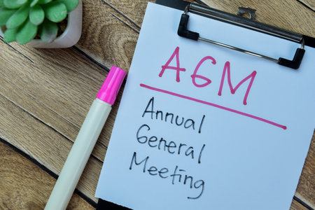 Concept of AGM - Annual General Meeting write on paperwork isolated on Wooden Table.の写真素材