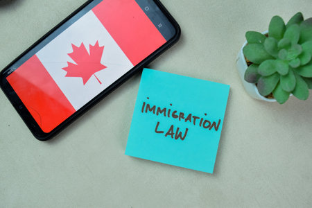 Concept of Immigration Law write on sticky notes isolated on Wooden Table.