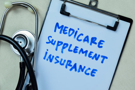 Concept of Medicare Supplement Insurance write on book with stethoscope isolated on Wooden Table.の写真素材