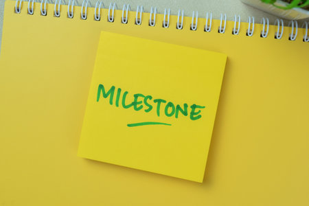 Concept of Milestone write on book isolated on Wooden Table.