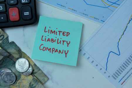 Concept of Limited Liability Company write on sticky notes with Indonesian Currency isolated on Wooden Table.の写真素材