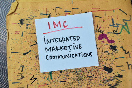 Concept of IMC - Integrated Marketing Communications write on sticky notes isolated on Wooden Table.