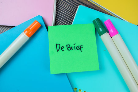 Concept of Debrief write on sticky notes isolated on Wooden Table.