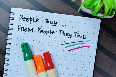Concept of People Buy From People They Trust write on book isolated on Wooden Table.の写真素材