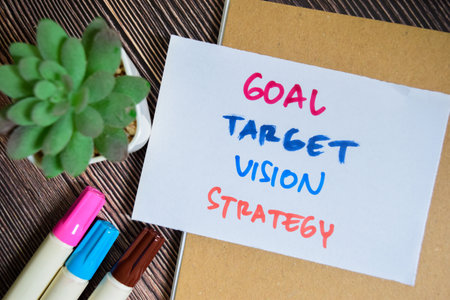 Concept of Goal, Target, Vision, Strategy write on sticky notes isolated on Wooden Table.の写真素材