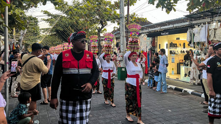 Procession of beautiful Balinese women in traditional costumes - sarong, carry offering on heads for...
