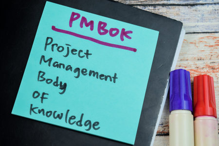 Concept of PMBOK - Project Management Body of Knowledge write on sticky notes isolated on Wooden Table.の写真素材
