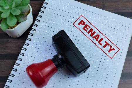 Red Handle Rubber Stamper and Penalty text above book isolated on wooden background