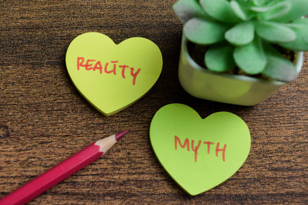 Concept of Reality or Myth write on sticky notes isolated on Wooden Table.