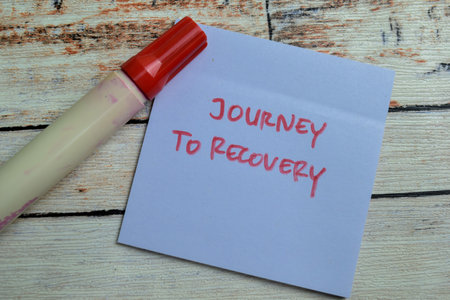 Concept of Journey to Recovery write on sticky notes isolated on Wooden Table.