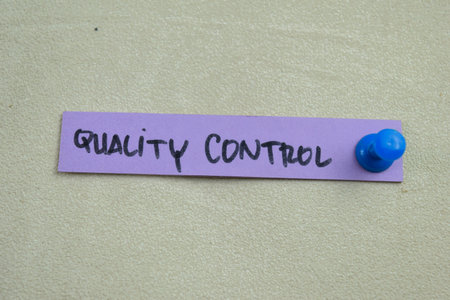 Concept of Quality Control write on sticky notes isolated on Wooden Table.
