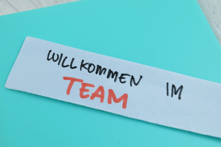 Concept of Willkommen Im Team write on sticky notes isolated on Wooden Table.の写真素材