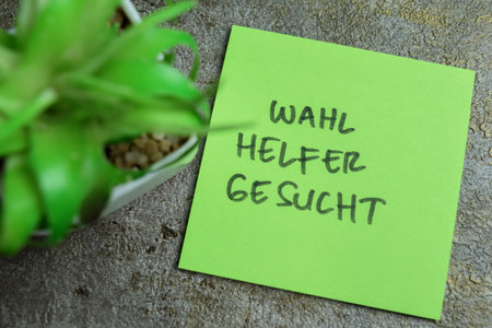 Concept of Learning language - German. Wahl Helfer Gesucht it means Election helper wanted written on sticky notes. German language isolated on Wooden Table.の写真素材