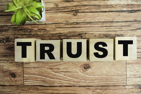 Concept of The wooden Cubes with the word Trust on wooden background.
