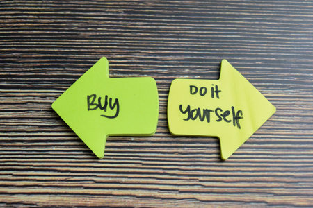 Concept of Buy or Do it yourself write on sticky notes isolated on Wooden Table.の写真素材