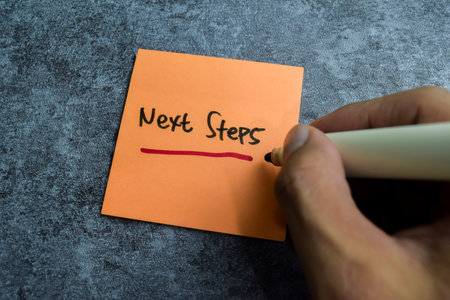 Concept of Next Steps write on sticky notes isolated on Wooden Table.