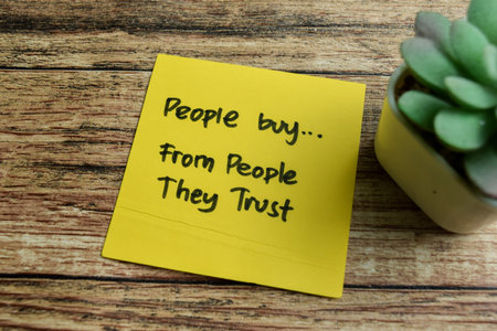 Concept of People Buy, From People They Trust write on sticky notes isolated on Wooden Table.の写真素材