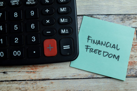 Concept of Financial Freedom write on sticky notes isolated on Wooden Table.